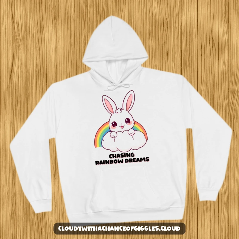 Funny hoodie with a cheerful bunny peeking from behind a puffy cloud, holding a rainbow, offering cozy enchantment.