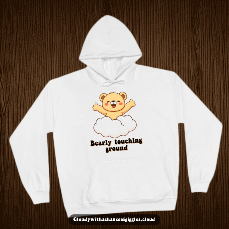 Funny bear cub gleefully riding a fluffy cloud with arms outstretched, a cozy and humorous hoodie for embracing dreams and carefree joy.